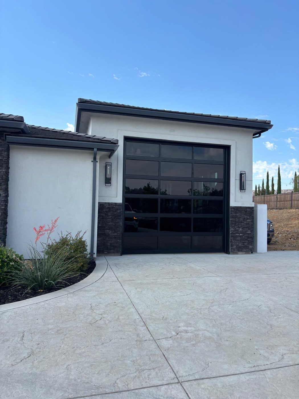 Modern black steel garage door with tinted window panels on a contemporary home