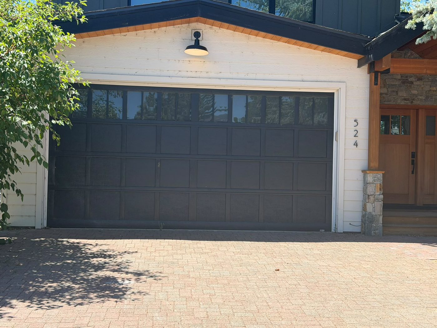 Black carriage-style garage door with a row of top windows on a modern farmhouse