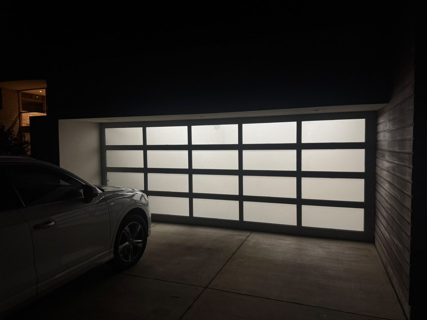 Frosted full-view garage door glowing from inside at night